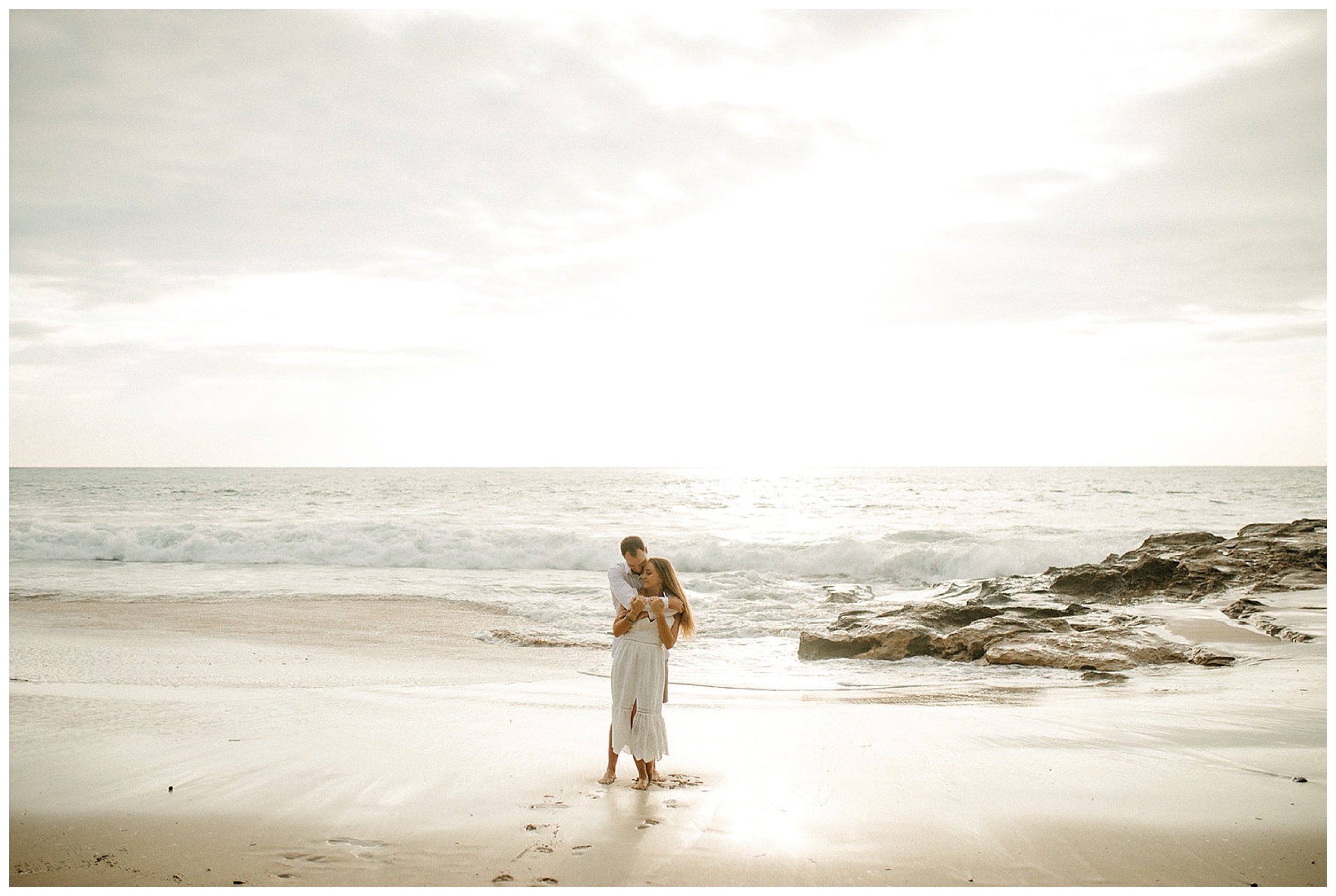 couple hugging on beach in hawaii
