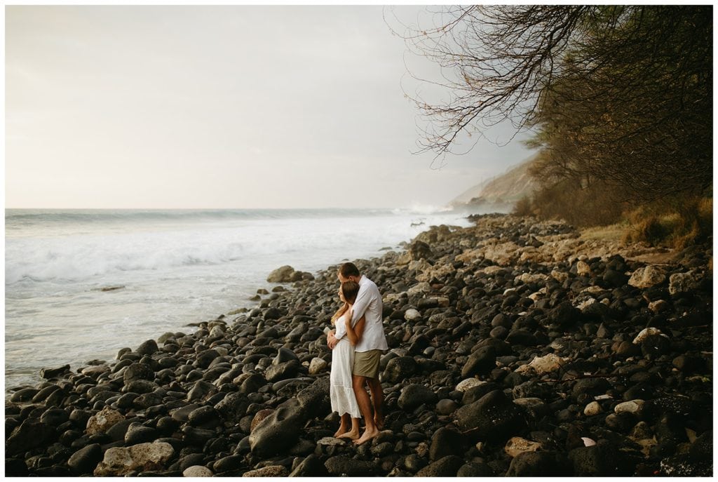 couple hugging on rocks by beach