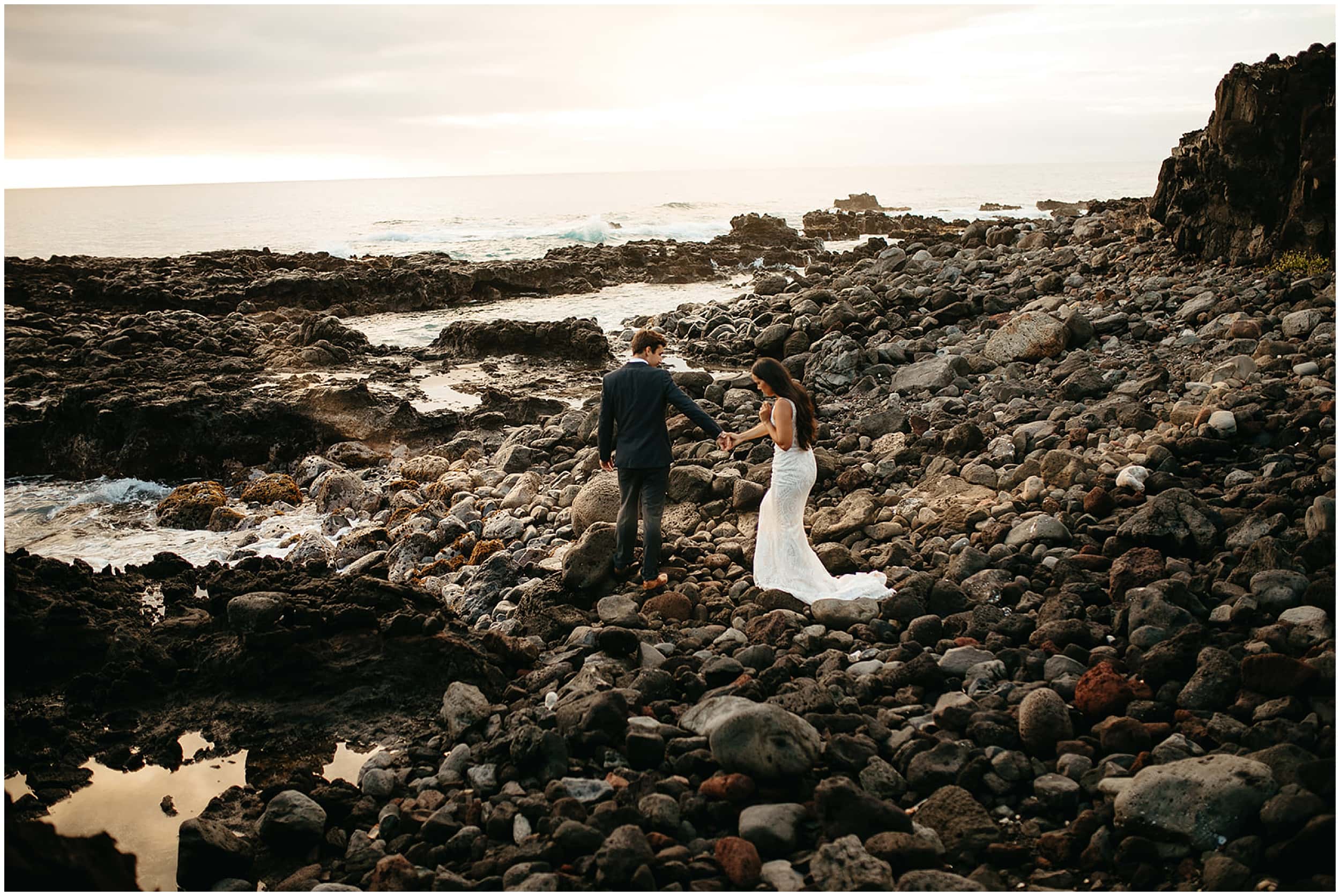 bride and groom walking on rocky beach