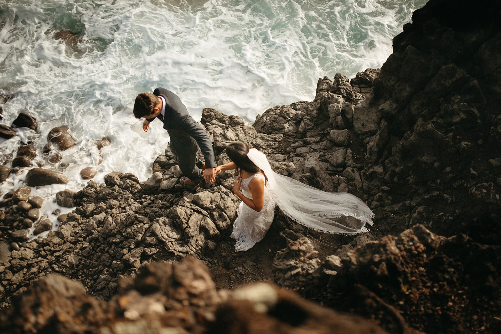 bride and groom walking on rocks