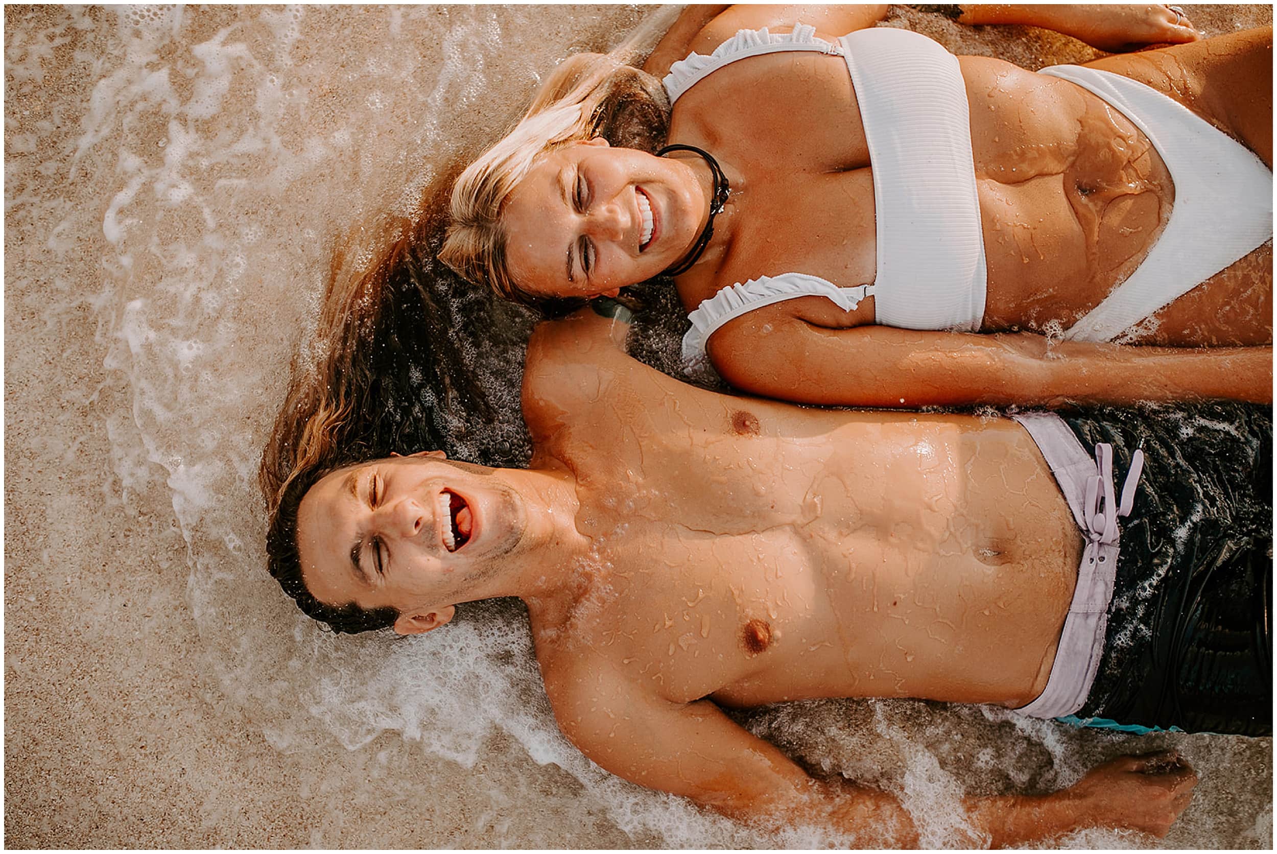 couple laying in ocean waves