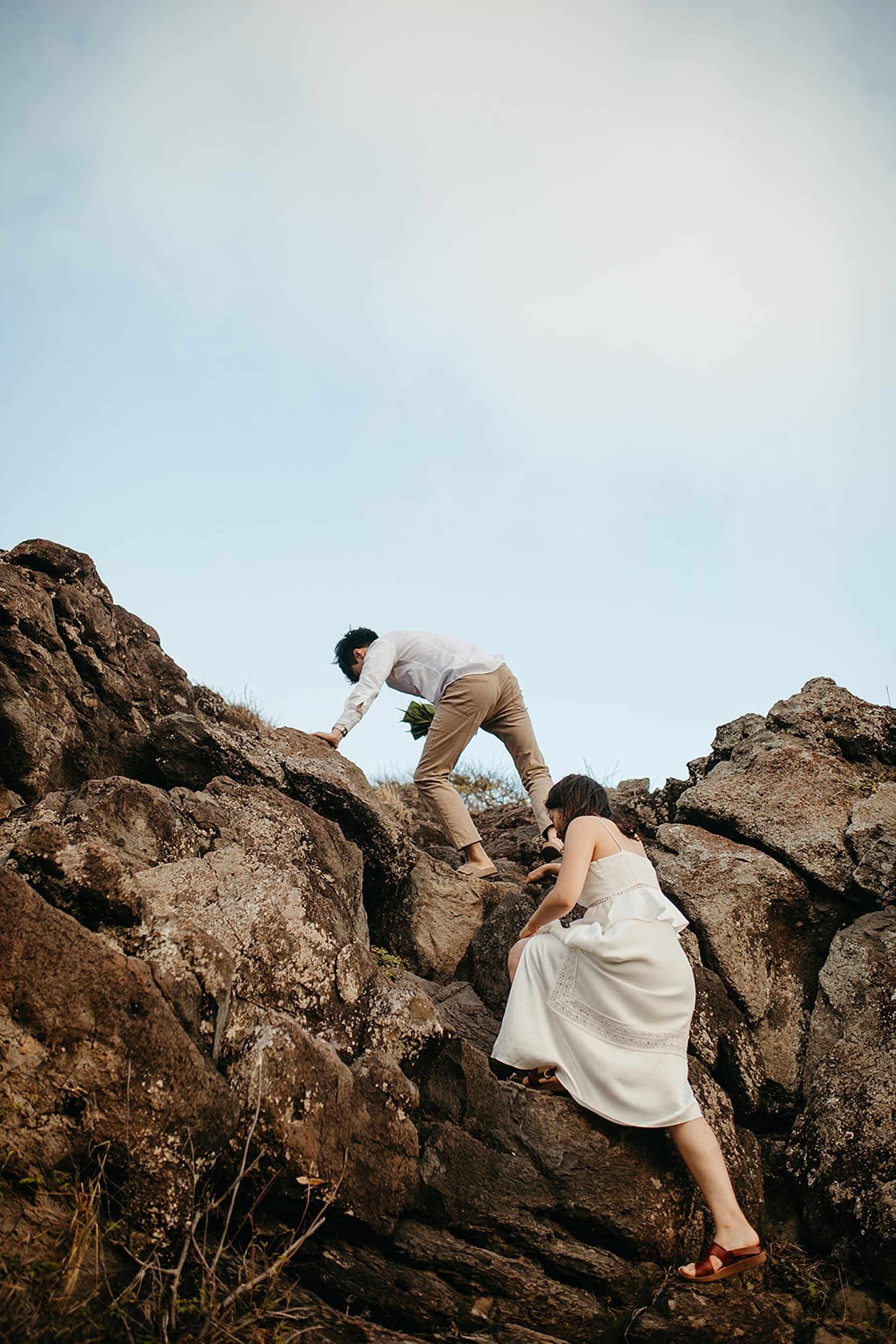 couple climbing rock during a Hawaii elopement