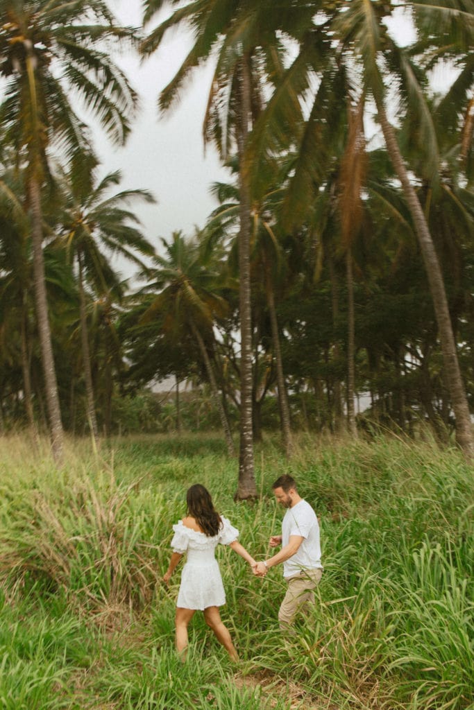 couple is holding hands and walking in tropical forest