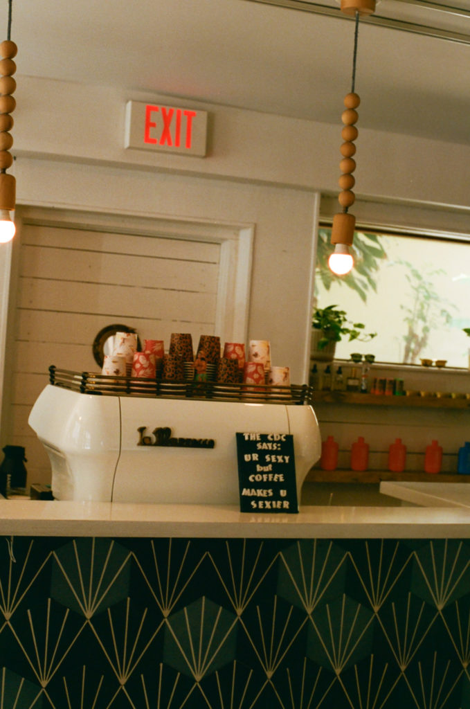 film picture of the inside of the coffee shop of the Surf Jack hotel with a board that says "the CDC says you're sexy but coffee makes you sexier"
