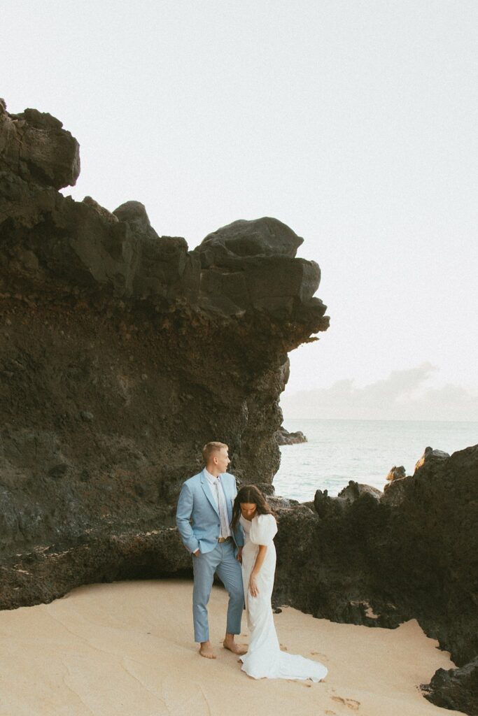 shot of the couple standing in front of a rocky cliff and looking off into the distance
