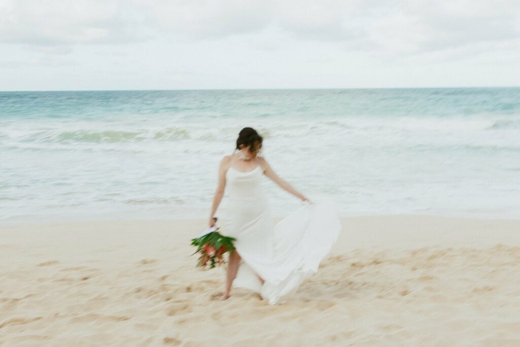blurry candid of the bride playing with her dress at the beach