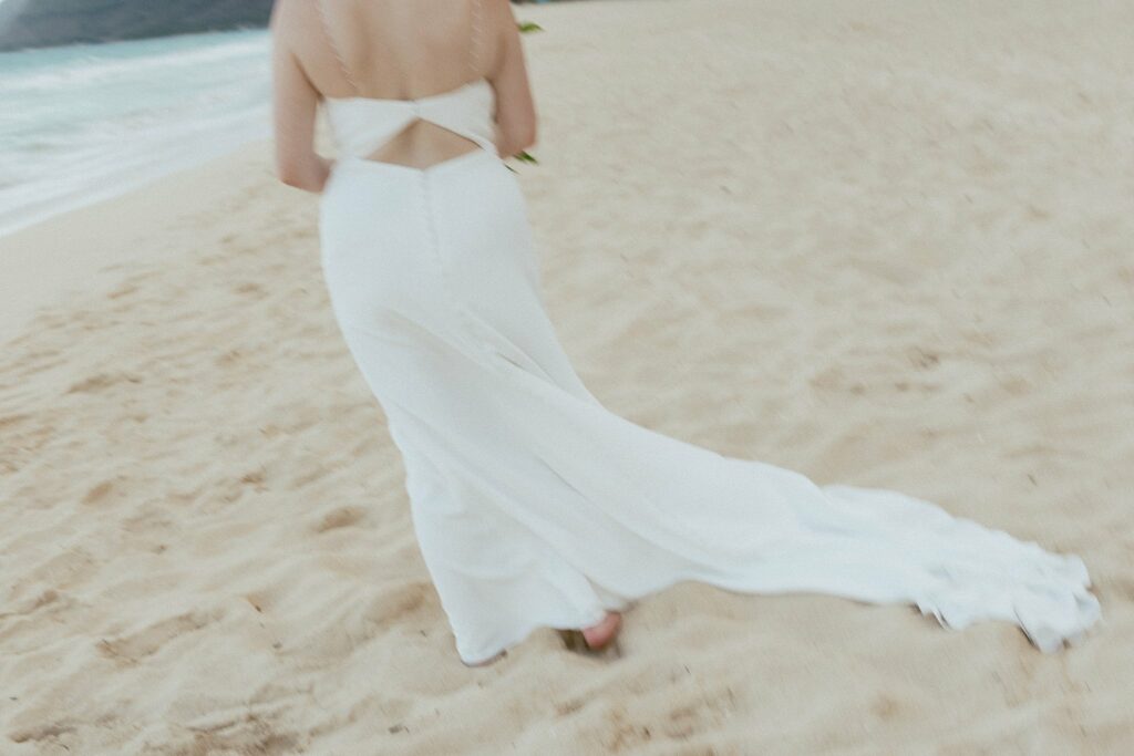 blurry shot of the brides wedding dress on the beach