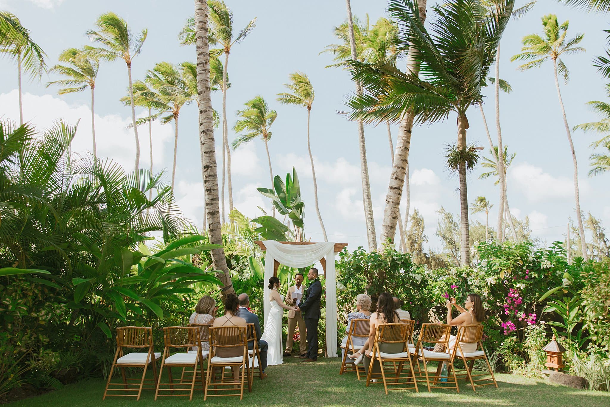shot of margot and tony getting married at the alter with a tropical background