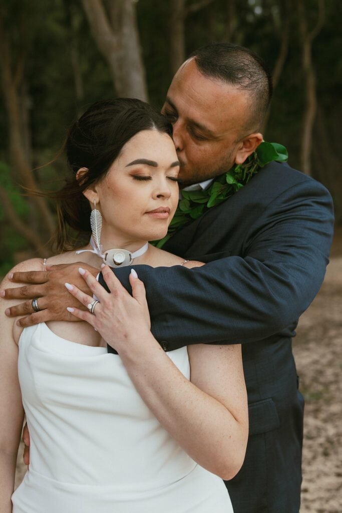 portrait of groom kissing bride on the forehead from the behind