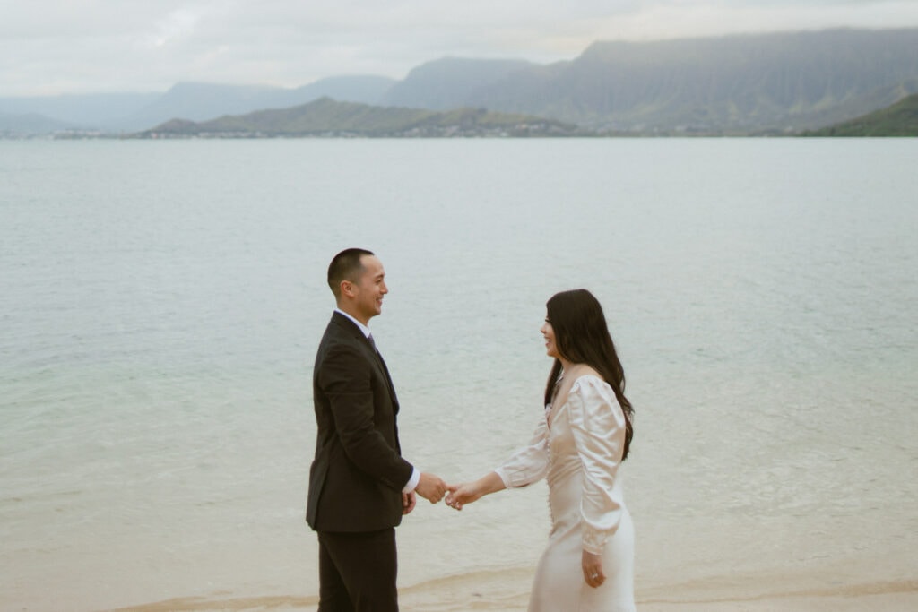 couple is holding hands while standing along the shoreline