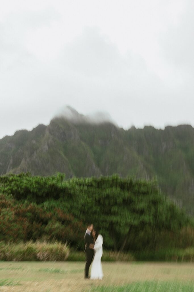 blurry portrait of the couple hugging eachother in front of the mountains