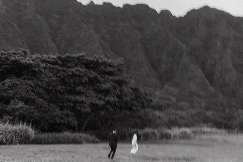 blurry black and white photo of the couple running together in front of the mountains
