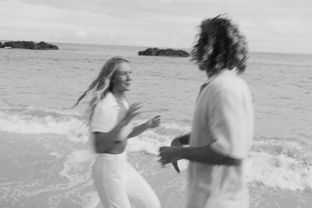 black and white blurry shot of the couple playing with each other at the beach