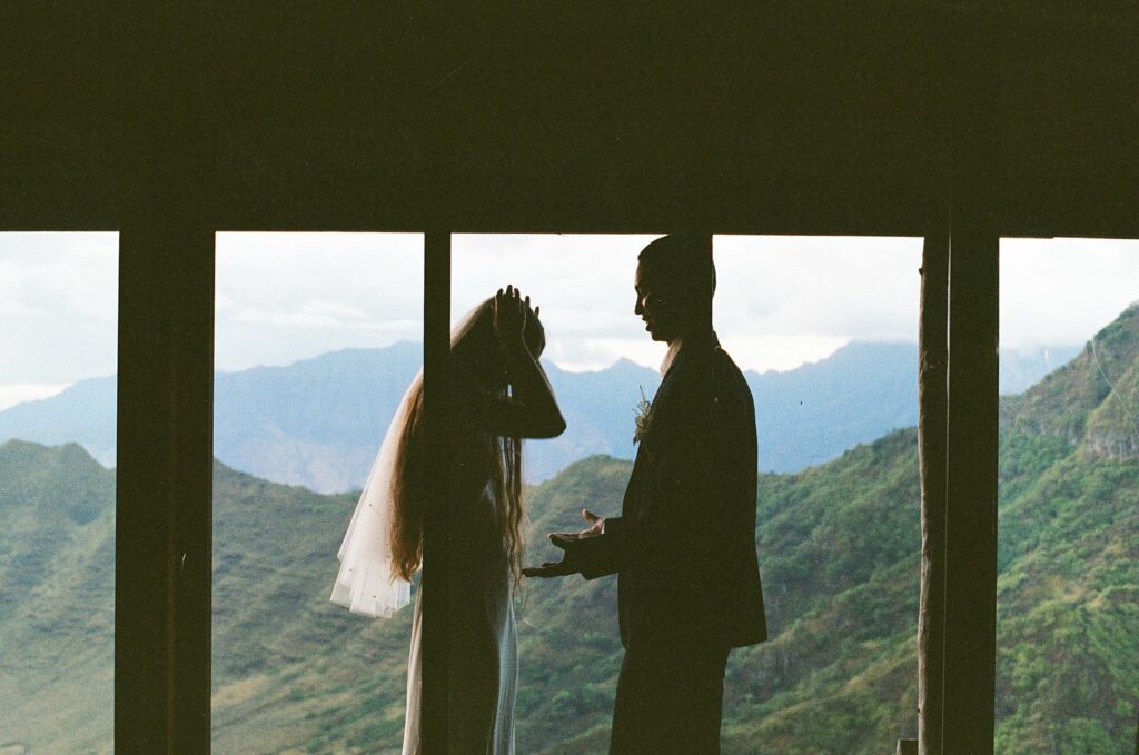 film shot of the bride putting her veil on with the groom