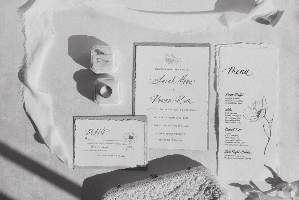 black and white shot of the invitations and rings