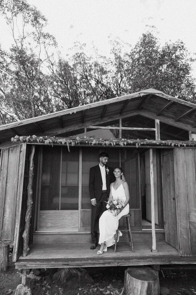 black and white shot of the bride and groom sitting outside the cabin