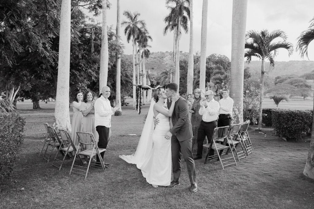 black and white shot of bride and groom kissing at the end of the alter