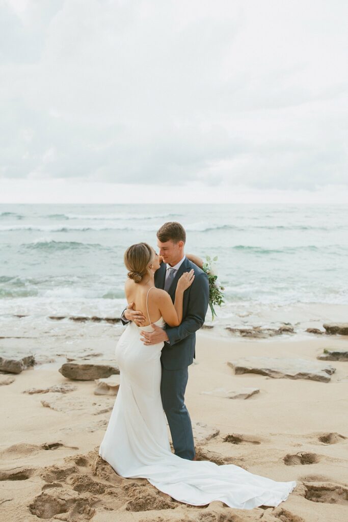 shot of bride and groom hugging on the beach