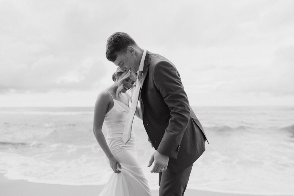 editorial black and white shot of bride and groom on the beach