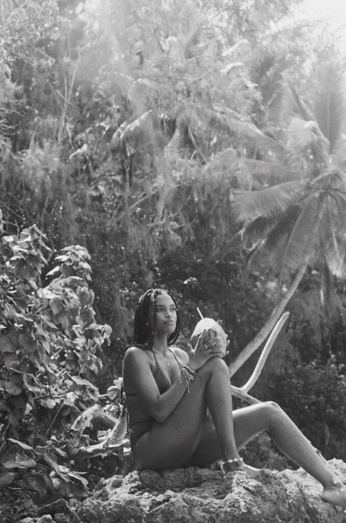 black and white shot of model sipping coconut on the beach