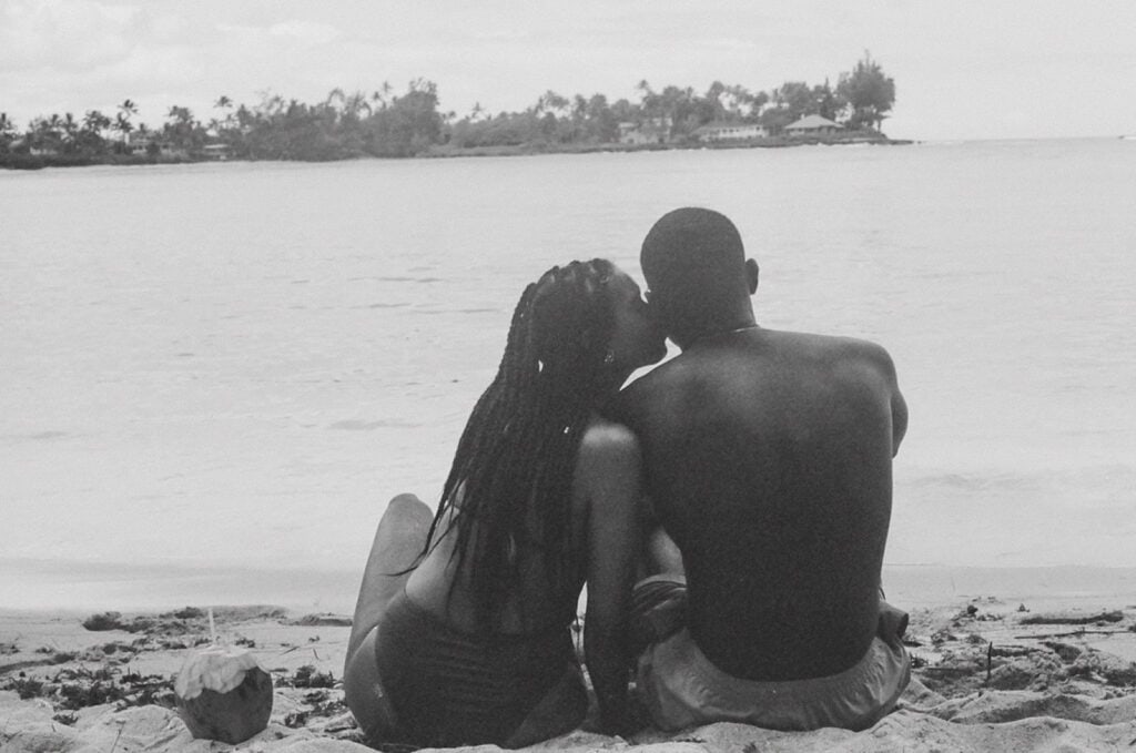 black and white film pic of couple sitting down on the beach, honeymooning in hawaii