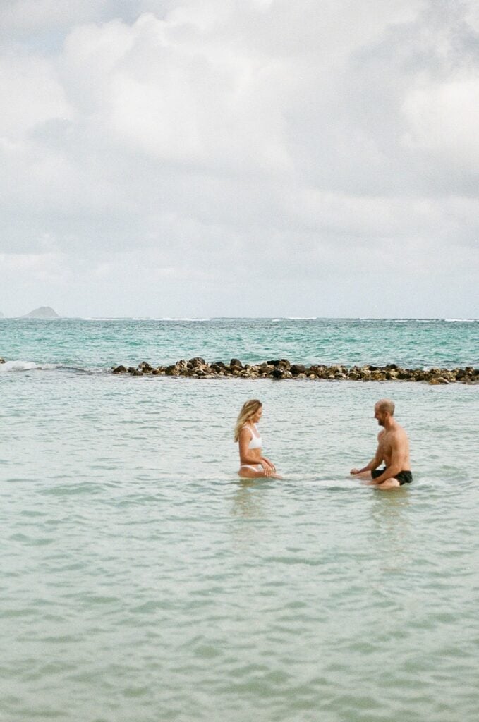 couple is sitting on their surfboards in the ocean