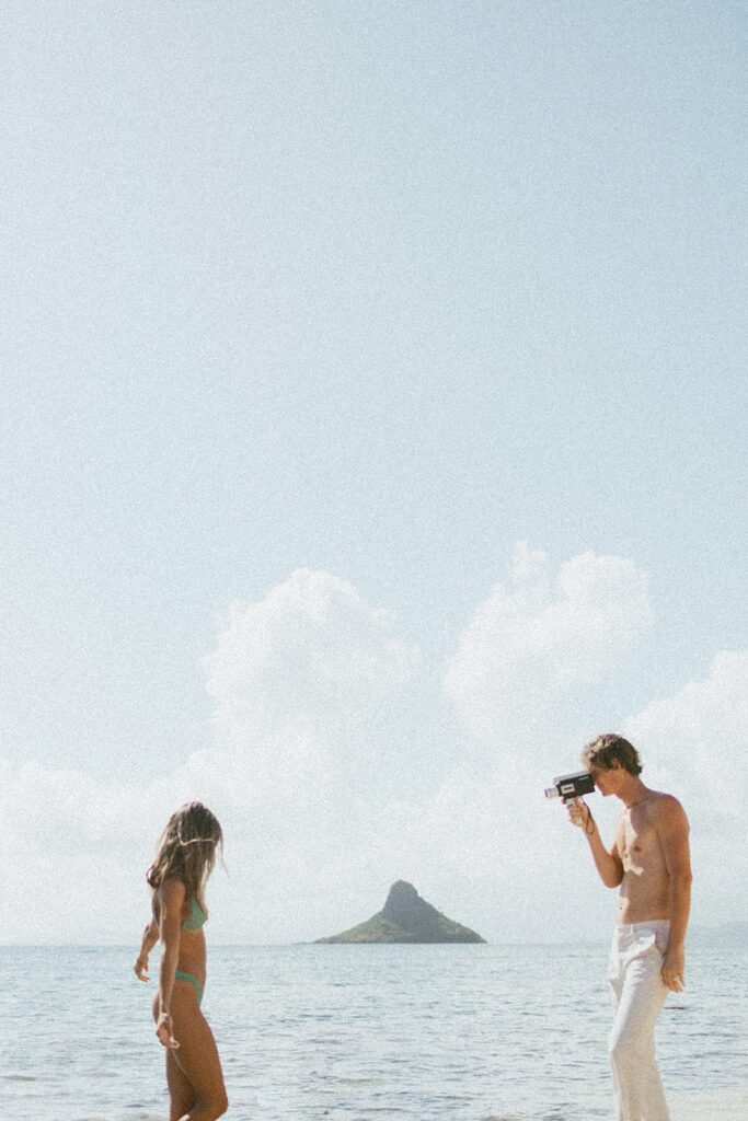 guy is taking photo of girl while they are honeymooning in hawaii