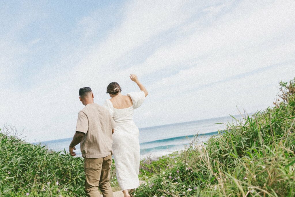 couple is walking togethe towards the beach during their hawaii maternity photoshoot