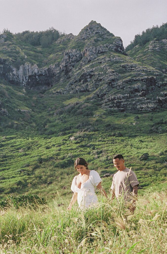 film photo of couple walking in front of the mountains
