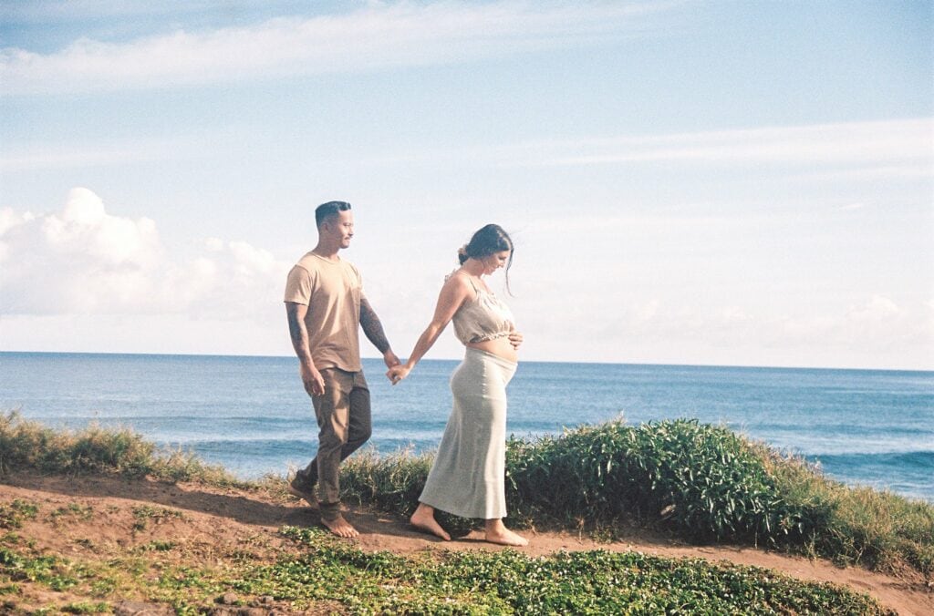 film photo of couple holding hands and walking along the beach 