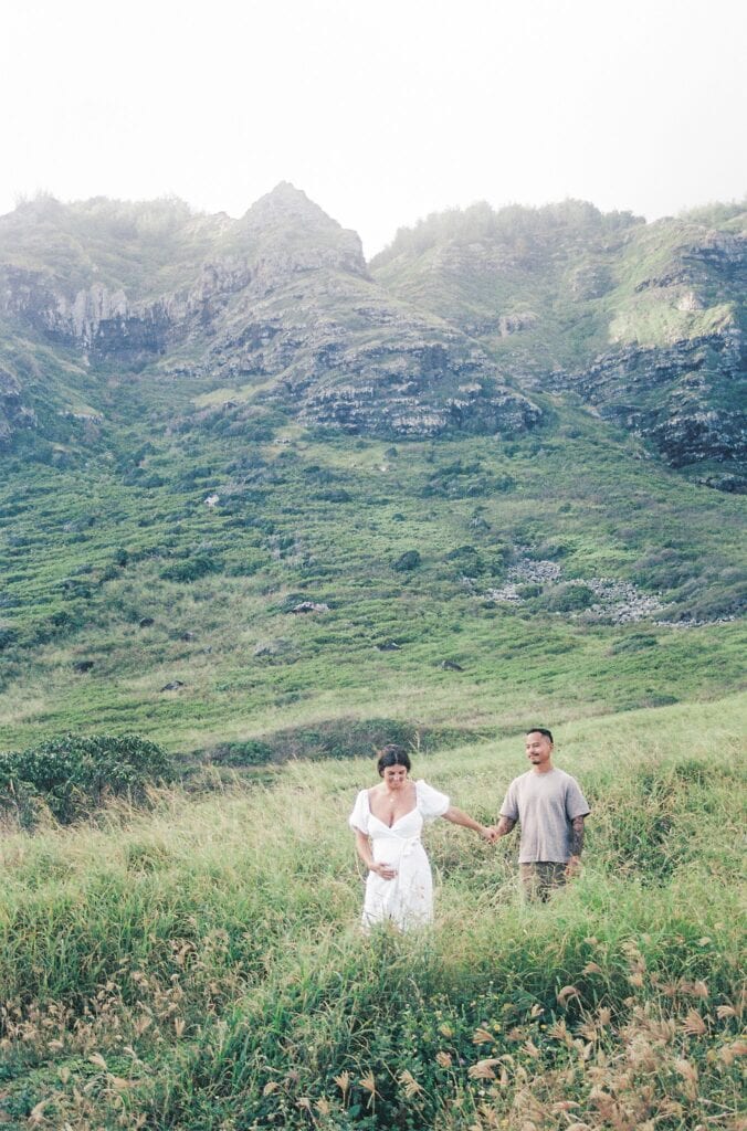 film photo of couple walking while holding hands along the mountain range 