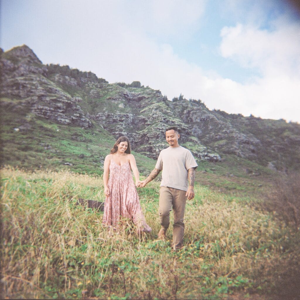 film photo of the couple holding hands with mountain scenery in the back