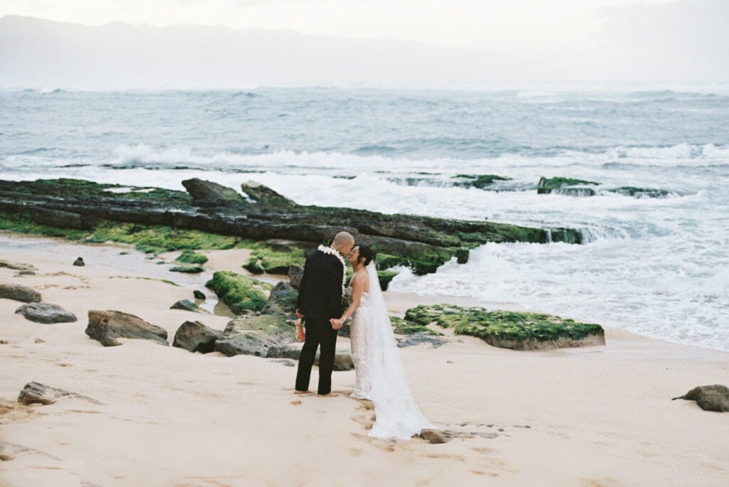 bride and groom kissing at sunset on the beach